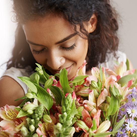 At Floral Design Studio, a woman inhales the scent of vibrant blooms with closed eyes.