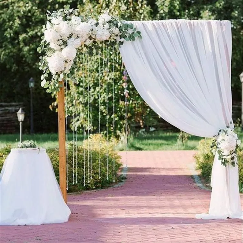 Best wedding florist creates stunning floral arches, adorned with cascading white fabric, marking the start of a charming brick-lined pathway.