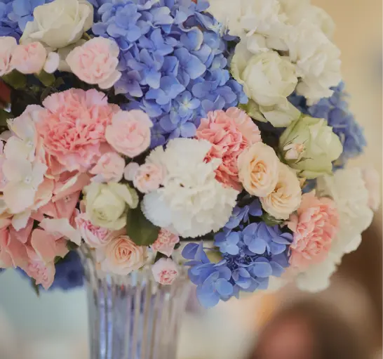 Close-up of a tall glass vase filled with a vibrant mix of pink, blue, and white flowers arranged by Sacramento's premier floral design company.