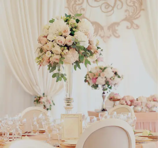 Elegantly set wedding reception tables with a floral design company in Sacramento and place settings in a banquet hall.